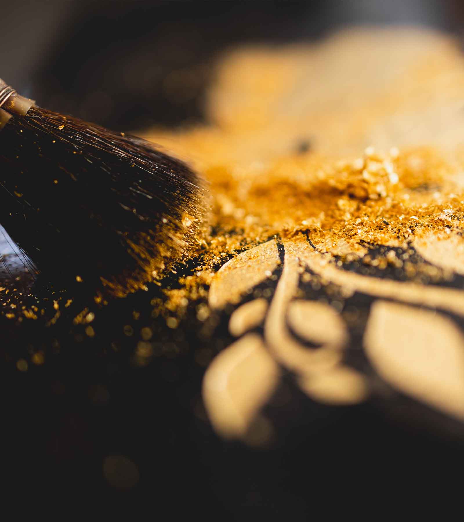 Nahaufnahme von goldenen Pigmenten auf der schwarzen Grabplatte.