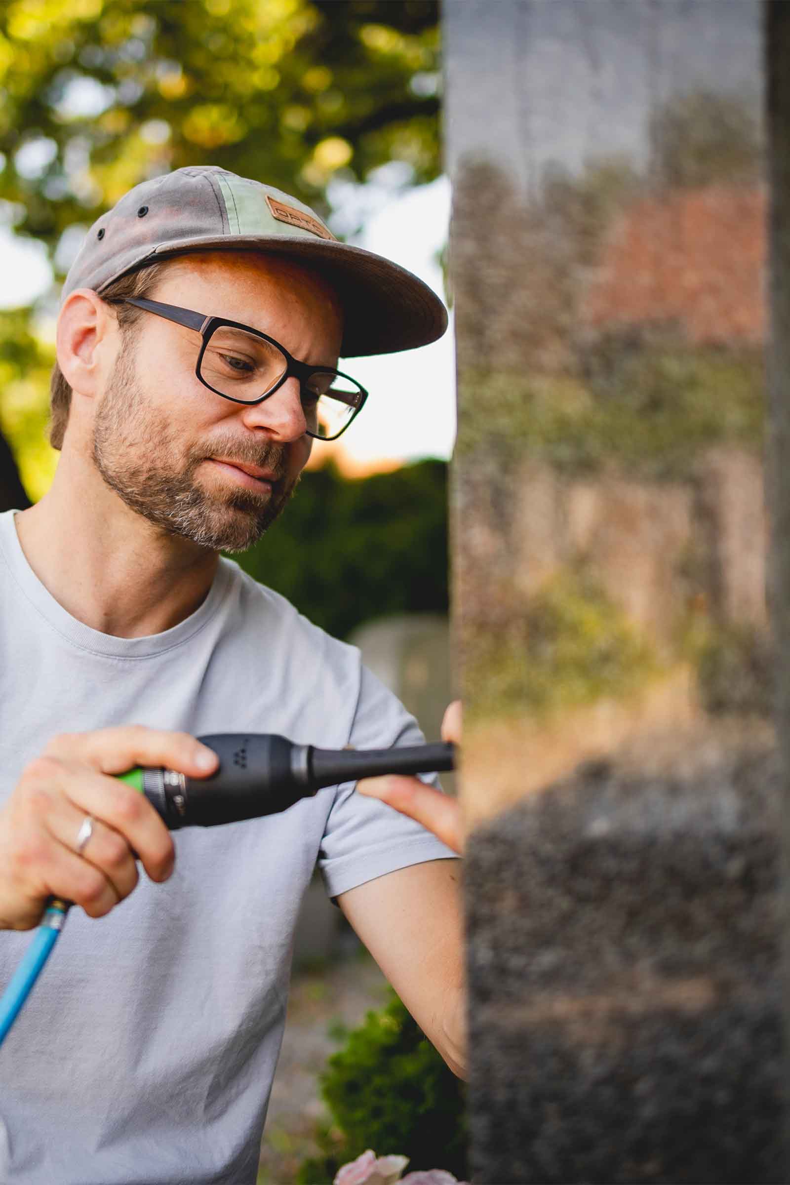 Steinmetz Florian Stöberl arbeitet auf dem Friedhof an einem Grabstein bei Sonnenschein